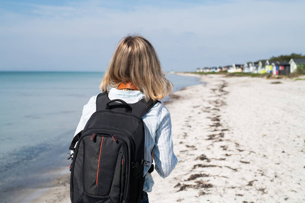 kobieta z plecakiem spaceruje po plaży - Zdjęcie, obraz