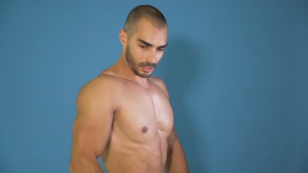 Modelo Fitness Masculino posando y mostrando músculos tríceps, aislados sobre fondo azul
 - Metraje, vídeo