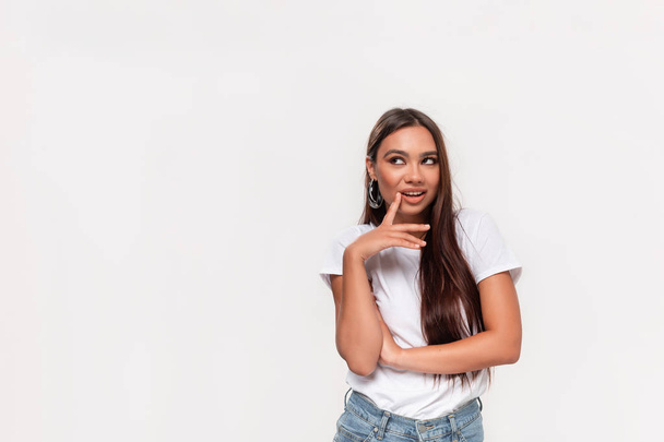 Pretty african-american teenager in a white tee and blue jeans thinking smiling isolated over white background. Copy space for advertising. - Photo, Image