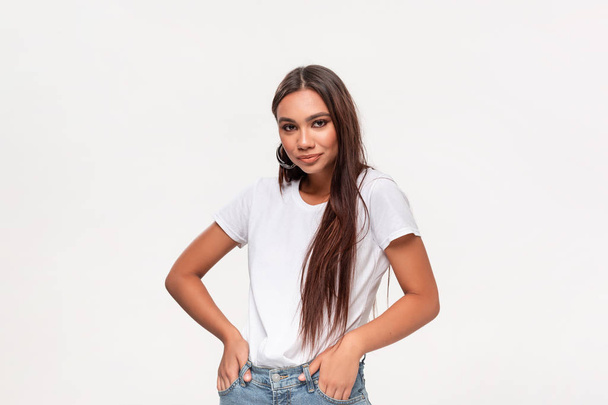 Beautiful african-american teenager in a white t-shirt and blue jeans isolated over white background. - Fotó, kép