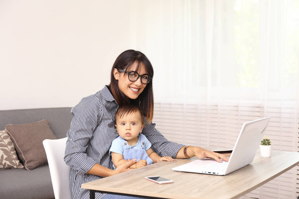 Young mother working at home office with her child, white wall background with copy space. - Foto, Imagem