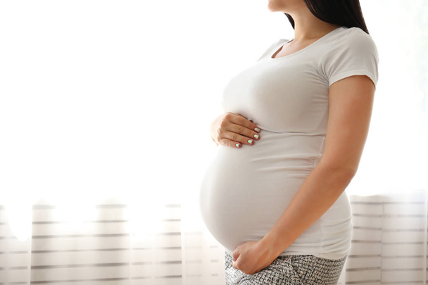 Nuori nainen pitää hänen raskaana vatsa yhdeksännellä raskauskuukaudella
. - Valokuva, kuva