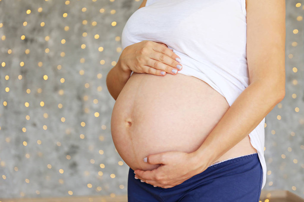 Young woman holding her pregnant belly on ninth month of pregnancy. - Valokuva, kuva