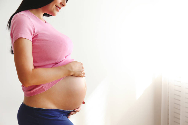 Young woman holding her pregnant belly on ninth month of pregnancy. - Φωτογραφία, εικόνα