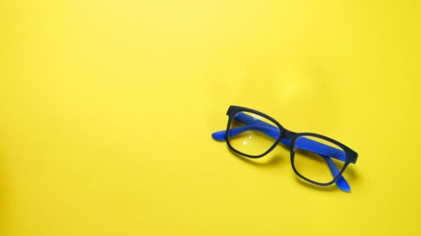Human hands search, find and take eye glasses in blue plastic frame. On yellow background. - Footage, Video
