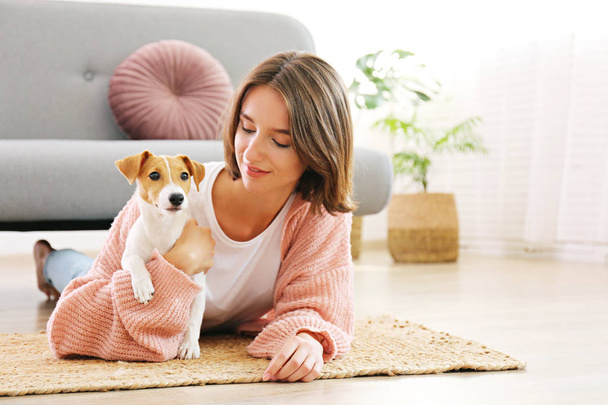 Portrait of young beautiful hipster woman with her adorable four months old jack russell terrier puppy at home in living room full of natural sunlight. Lofty interior background, close up, copy space. - Foto, afbeelding