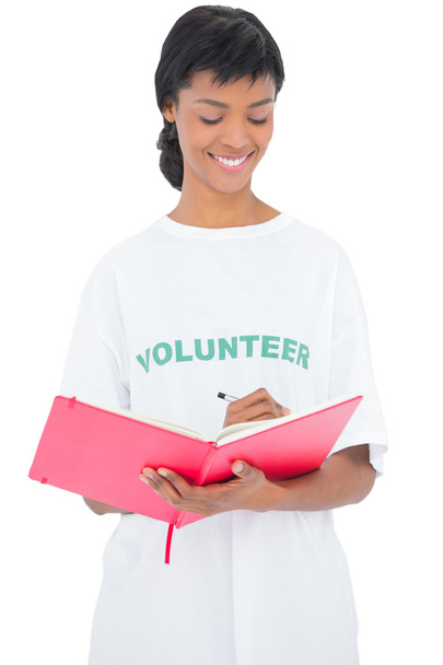 Pretty black haired volunteer writing on a notebook - Foto, Imagen