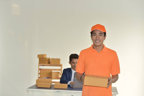 Szállítási szolgáltatás koncepció, fiatal ázsiai munkavállaló narancssárga egyenruhában csomagokat szállít üzletembereknek. - Fotó, kép