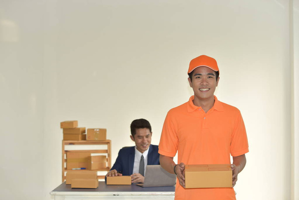 Concetto di servizio di consegna, giovane lavoratore asiatico in uniforme arancione consegna pacchetti per uomo d'affari
. - Foto, immagini