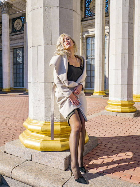 Blondes Mädchen auf einem Hintergrund weißer Säulen eines Gebäudes. - Foto, Bild
