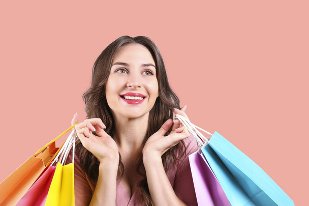 Black friday season sale concept. Attractive young woman with long brunette hair, wearing tight dress, holding many different blank shopping bags over pink isolated background. Copy space, close up - Foto, afbeelding
