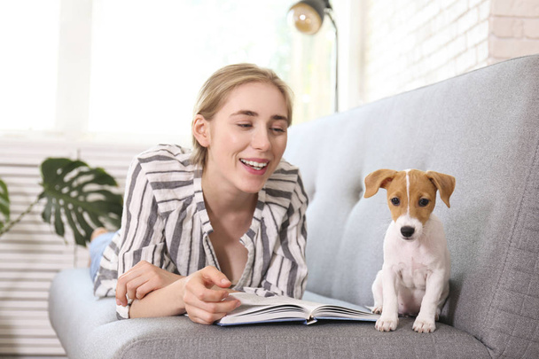 The cutest two months old Jack Russel terrier puppy with beautiful blonde young woman. Small adorable doggy with funny fur stains lying with owner. Close up, copy space, isolated background. - Foto, afbeelding