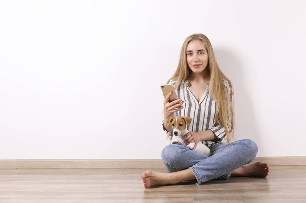 The cutest two months old Jack Russel terrier puppy with beautiful blonde young woman. Small adorable doggy with funny fur stains lying with owner. Close up, copy space, isolated background. - Foto, afbeelding