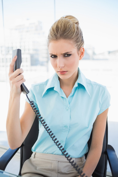 Frowning stylish businesswoman holding the phone - Фото, изображение