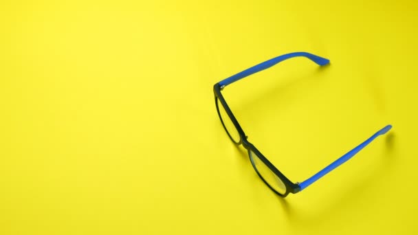 Les mains humaines recherchent, trouvent et prennent des lunettes dans un cadre en plastique bleu. Sur fond jaune
. - Séquence, vidéo