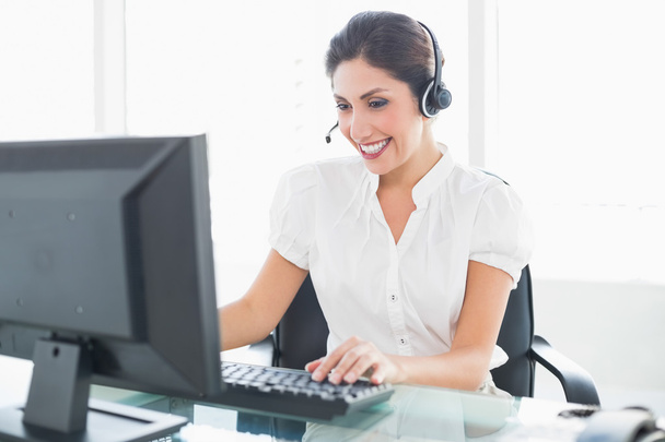 Cheerful call centre agent working at her desk on a call - Photo, Image