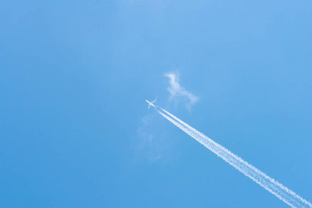 Літак у блакитному небі з хмарами та стежками конденсації (Німеччина). - Фото, зображення