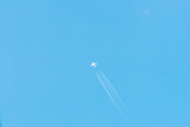 Літак у блакитному небі з хмарами та стежками конденсації (Німеччина). - Фото, зображення