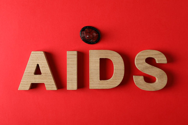 Palabra SIDA y preservativo sobre fondo rojo, espacio para texto
 - Foto, imagen