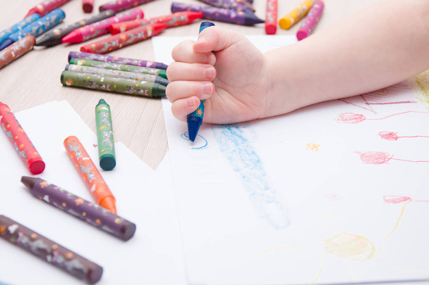 child draws a blue wax crayon cloud on paper - Foto, Imagen