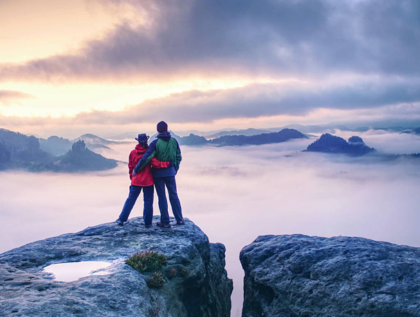 Paar auf dem Berg blickt über dichten Nebel zum Horizont - Foto, Bild