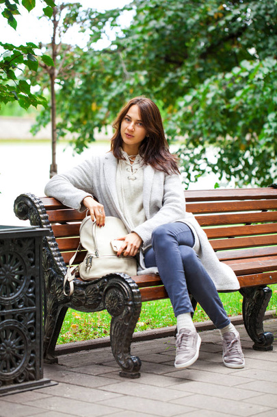 Young beautiful woman sitting on a bench in the autumn park - Fotografie, Obrázek
