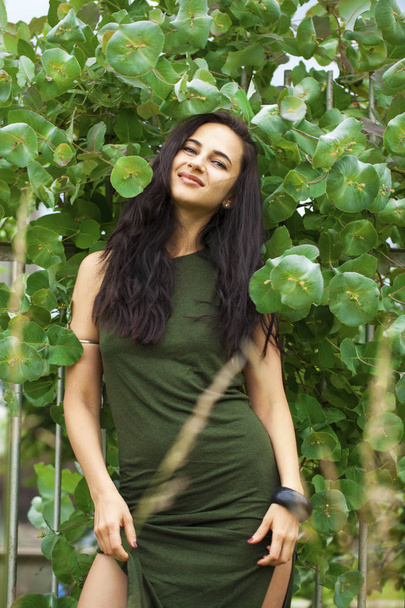 Portrait of a young beautiful woman in green foliage - Fotó, kép