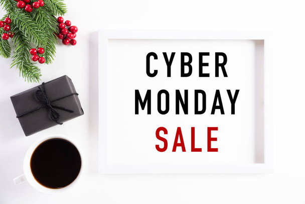 Top view of Cyber Monday Sale text on white picture frame with coffee cup, gift box and Christmas tree decoration, red berries on white background. Conceito de compras e composição Cyber Monday
. - Foto, Imagem