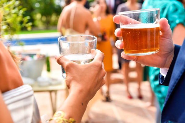 Gäste einer Veranstaltung halten Gläser mit Getränken und kaltem Bier in der Hand, während - Foto, Bild