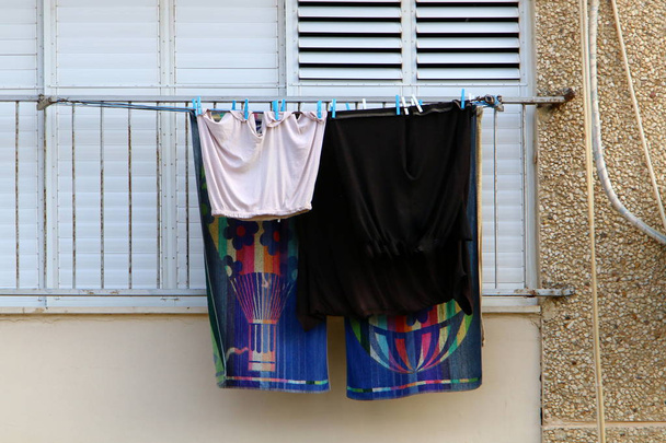 pieni ikkuna Israelin suurkaupungissa, jonka takana pestyt vaatteet kuivuvat
  - Valokuva, kuva