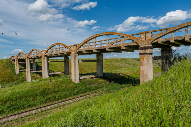 Старый бетонный мост в Скотсгарде, Словакия, с железнодорожными путями под ним
 - Фото, изображение