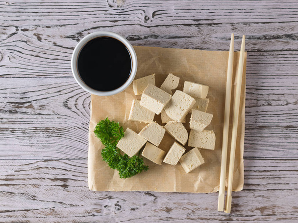 A piece of crumpled paper with soy sauce and slices of tofu cheese. Soy cheese. Flat lay. - Photo, Image