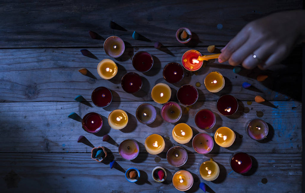Vela de iluminación encendida a mano sobre mesa de madera. Muchas llamas de velas en da
 - Foto, imagen