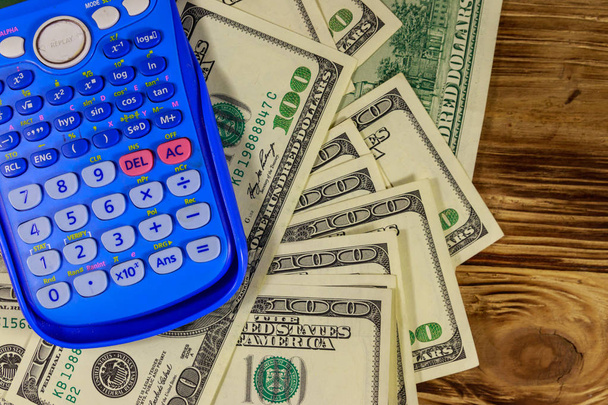 Calculatrice et billets en dollars américains sur table en bois. Vue du dessus
 - Photo, image