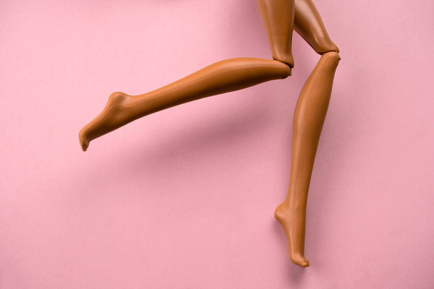 close up of smooth legs of a plastic toy doll on a soft pink background - Foto, afbeelding
