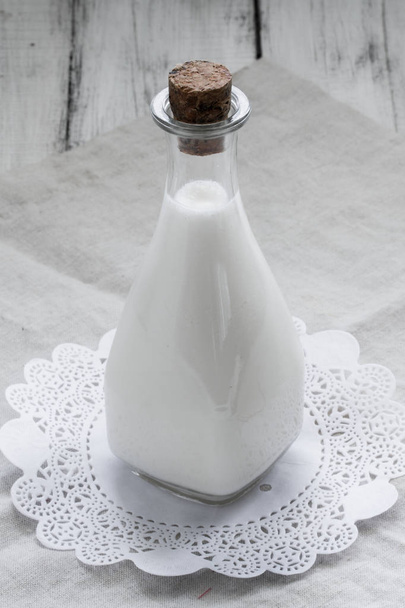 Coconut milk in a vintage bottle on rustic wooden background. - Foto, Imagem