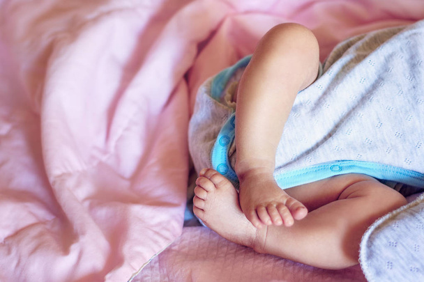 Small legs of the newborn baby on a pink blanket background, close-up, copyspase - Φωτογραφία, εικόνα
