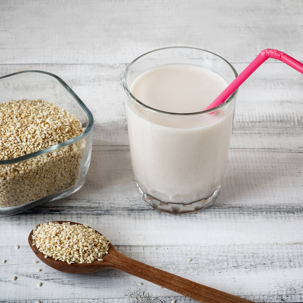 Sesame seed milk in a glass. White sesame seeds on a table. Raw food diet. - Foto, Imagem