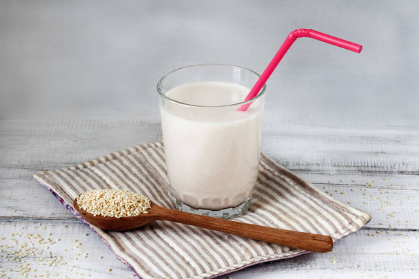 Sesame seed milk in a glass. White sesame seeds on a table. Raw food diet. - Foto, Imagem