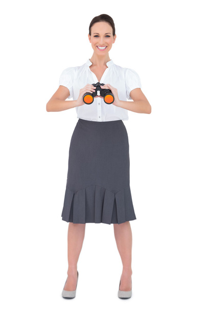 Smiling elegant businesswoman holding binoculars - 写真・画像