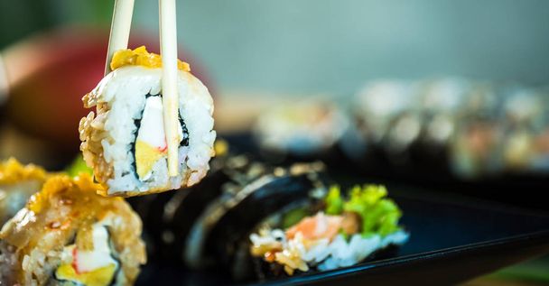 Person eating fresh Japanese sushi rolls, popular asian food. - Photo, Image