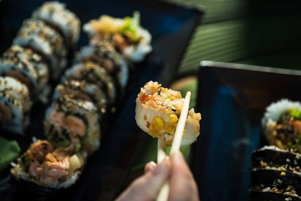 Person isst frische japanische Sushi-Rollen, beliebtes asiatisches Essen. - Foto, Bild