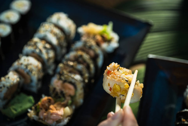 Personne mangeant des rouleaux de sushi japonais frais, nourriture asiatique populaire
. - Photo, image