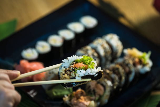 Человек, который ест свежие японские суши, популярные азиатские блюда
. - Фото, изображение