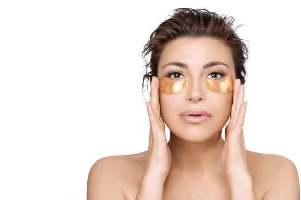 Woman using collagen eye patches to prevent skin aging. Golden h - Photo, Image