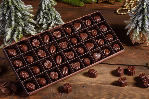 Assortiment van fijne chocolade snoepjes, witte, donkere, en melk chocolade snoepjes achtergrond. Kerst interieur met geschenkdozen en kerstvuren - Foto, afbeelding