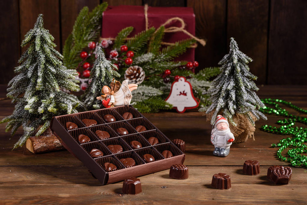 Εκχώρηση των λεπτών καραμέλες σοκολάτας, λευκό, σκούρο και σοκολάτα γάλακτος φόντο γλυκά. Χριστουγεννιάτικο εσωτερικό με κουτιά δώρων και φωτιές Χριστουγέννων - Φωτογραφία, εικόνα