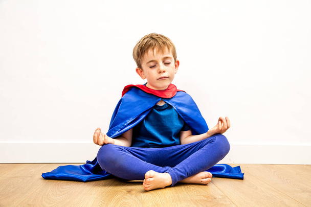serene superhero boy meditating with zen yoga, relaxation and mindfulness - Foto, Bild