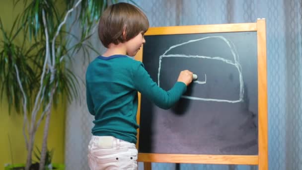 child draws a chalk house on a blackboard in kindergarten - Кадры, видео