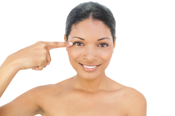 Smiling black haired model pointing at her eye - Photo, image